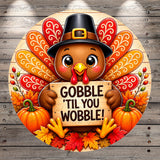 A cheerful cartoon turkey holding a sign that says "GOBBLE 'TIL YOU WOBBLE!" surrounded by autumn leaves, pumpkins, and a wooden background.