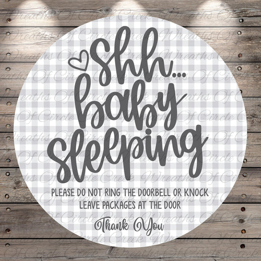 a circular sign with a message that says "Shh baby sleeping" in a playful, humorous font. The sign also includes a warning that says "Please do not ring the doorbell or knock. Leave packages at the door. Thank You."
