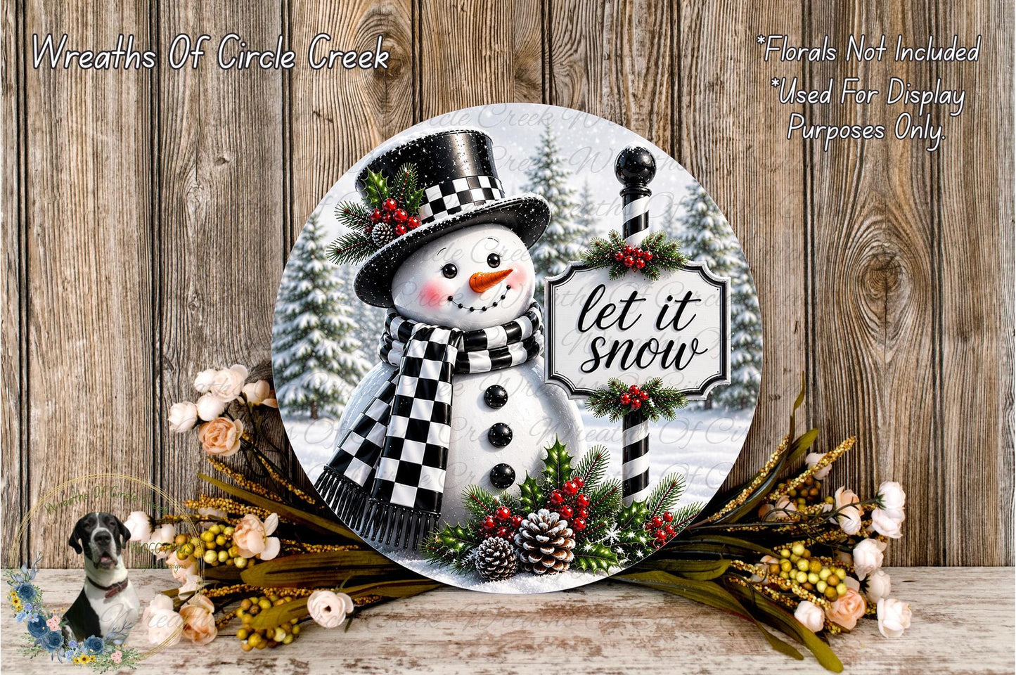 A snowman wearing a top hat and scarf, with a sign that says "let it snow", surrounded by pine cones, pine branches, and flowers, against a wooden background.