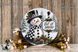 A snowman wearing a top hat and scarf, with a sign that says "let it snow", surrounded by pine cones, pine branches, and flowers, against a wooden background.