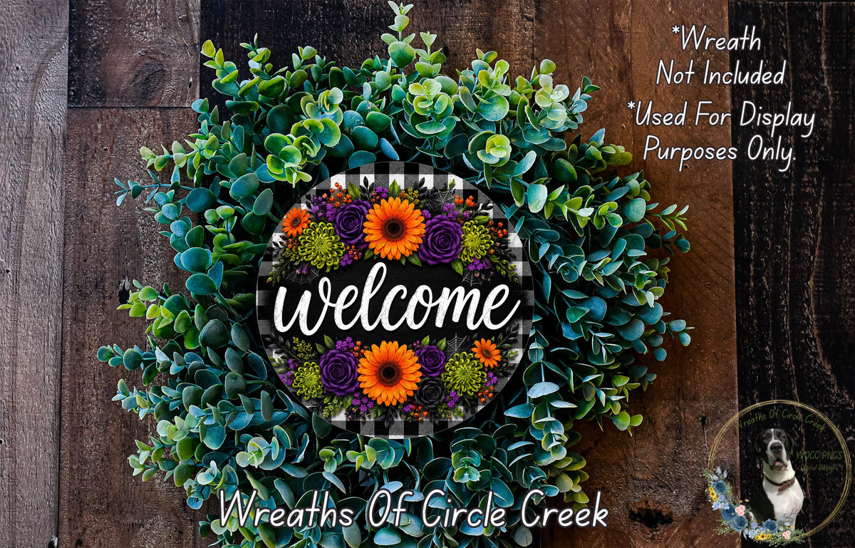 a wreath with a welcome sign in the center, surrounded by various green and purple flowers. The wreath is displayed on a wooden surface, and there is a small dog in the bottom right corner of the image.