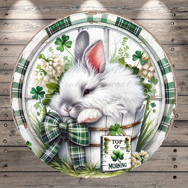 A white rabbit is sitting in a basket filled with flowers and shamrocks, surrounded by greenery, on a wooden surface.