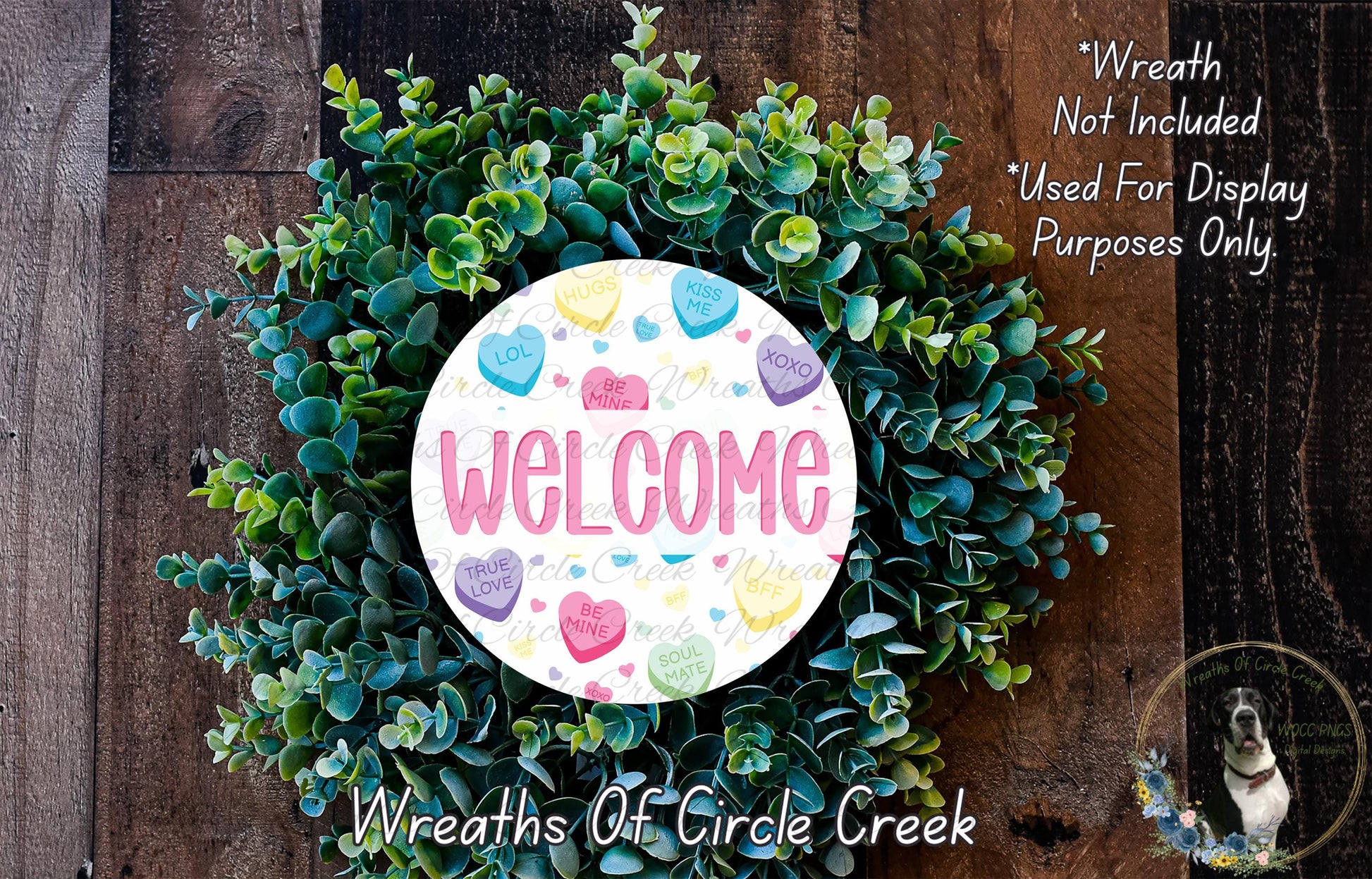 a wreath made of green leaves and flowers, with a white circular sign that says "Welcome" in the center. The sign is surrounded by the wreath, and there is a small dog visible in the bottom right corner of the image.