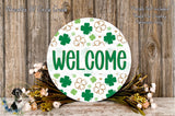 a circular sign with the word "WELCOME" written on it, surrounded by a wreath of flowers and greenery.