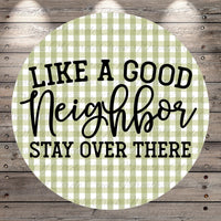 a circular design with a green and white checkered pattern. The design has the text "LIKE A GOOD NEIGHBOR STAY OVER THERE" written in a stylized font.