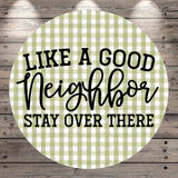 a circular design with a green and white checkered pattern. The design has the text "LIKE A GOOD NEIGHBOR STAY OVER THERE" written in a stylized font.