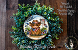A wreath featuring a cow wearing a cowboy hat and an American flag, surrounded by greenery and flowers.