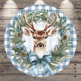 A deer head is depicted in a wreath made of pine cones, pine needles, and berries, with a blue ribbon bow.