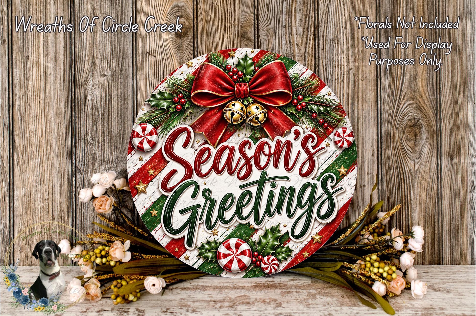 A festive wreath with the text "Season's Greetings" displayed prominently. The wreath is adorned with red and green ribbons, candy canes, and other holiday decorations. The wreath is placed on a wooden surface, surrounded by flowers.