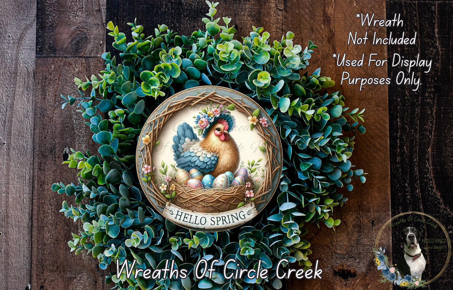 A wreath made of green foliage and featuring a rooster and the text "Hello Spring" is displayed on a wooden surface.