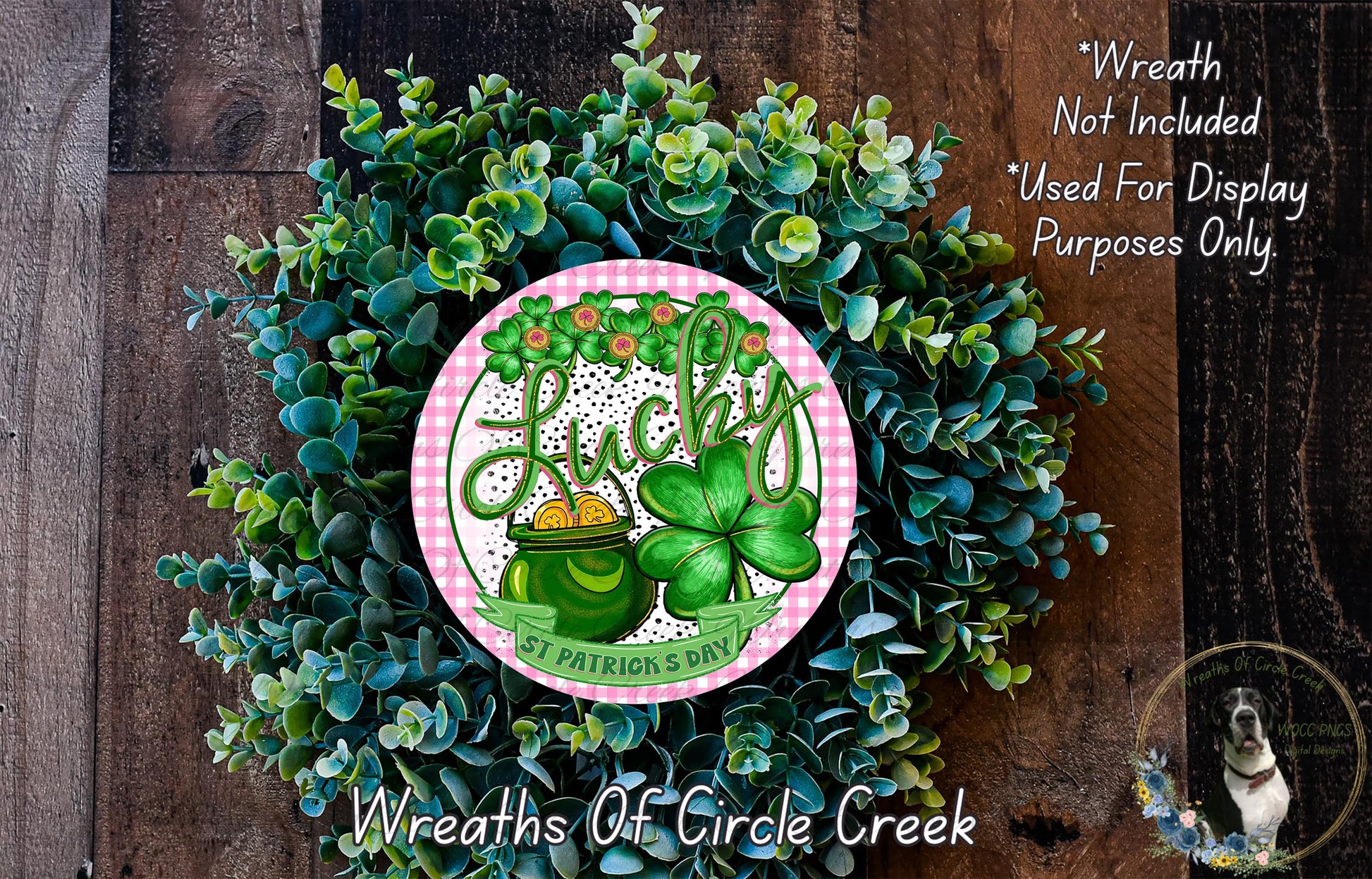 A wreath made of green leaves and a clover, with a pink and white circular sign featuring the word "Lucky" and an illustration of a pot of gold.