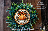 a wreath with a pumpkin and a bow, surrounded by greenery, with the word "WELCOME" displayed on the wreath.