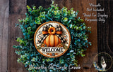 a wreath with a pumpkin and a bow, surrounded by greenery, with the word "WELCOME" displayed on the wreath.