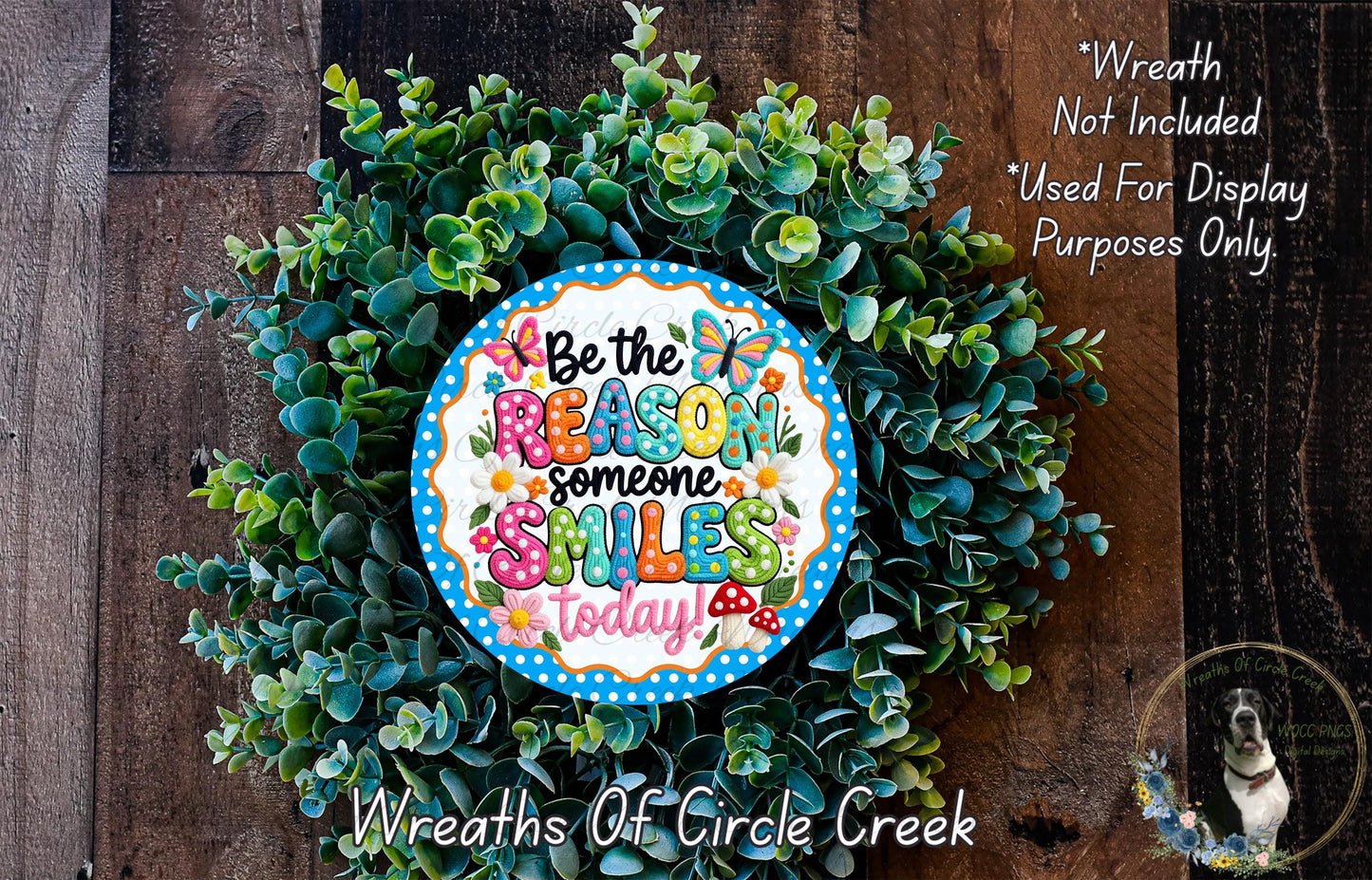 a wreath made of green leaves and flowers, with a colorful sign that reads "Be the reason someone smiles today".