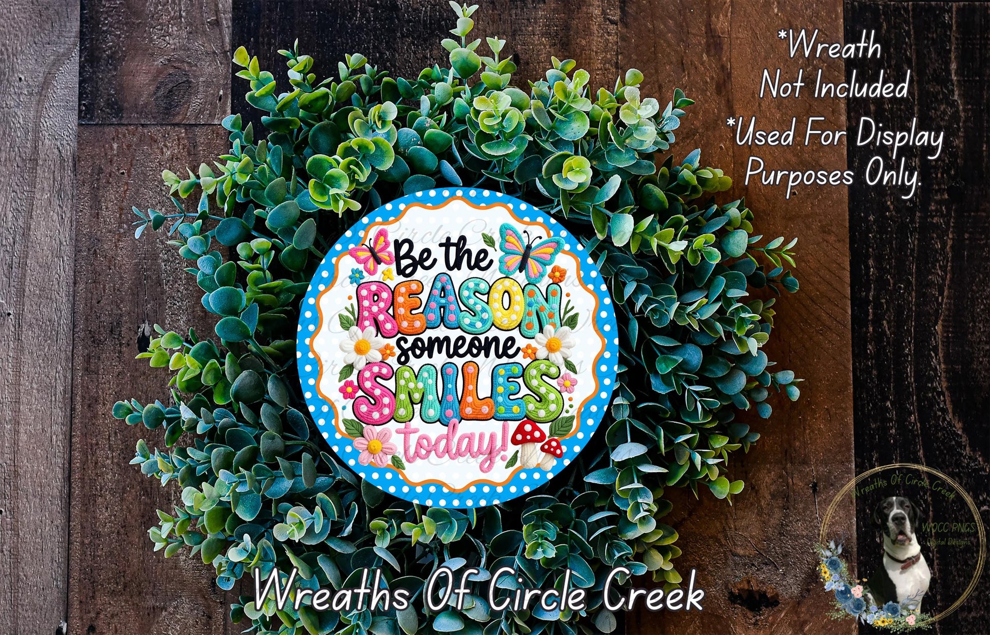 a wreath made of green leaves and flowers, with a colorful sign that reads "Be the reason someone smiles today".