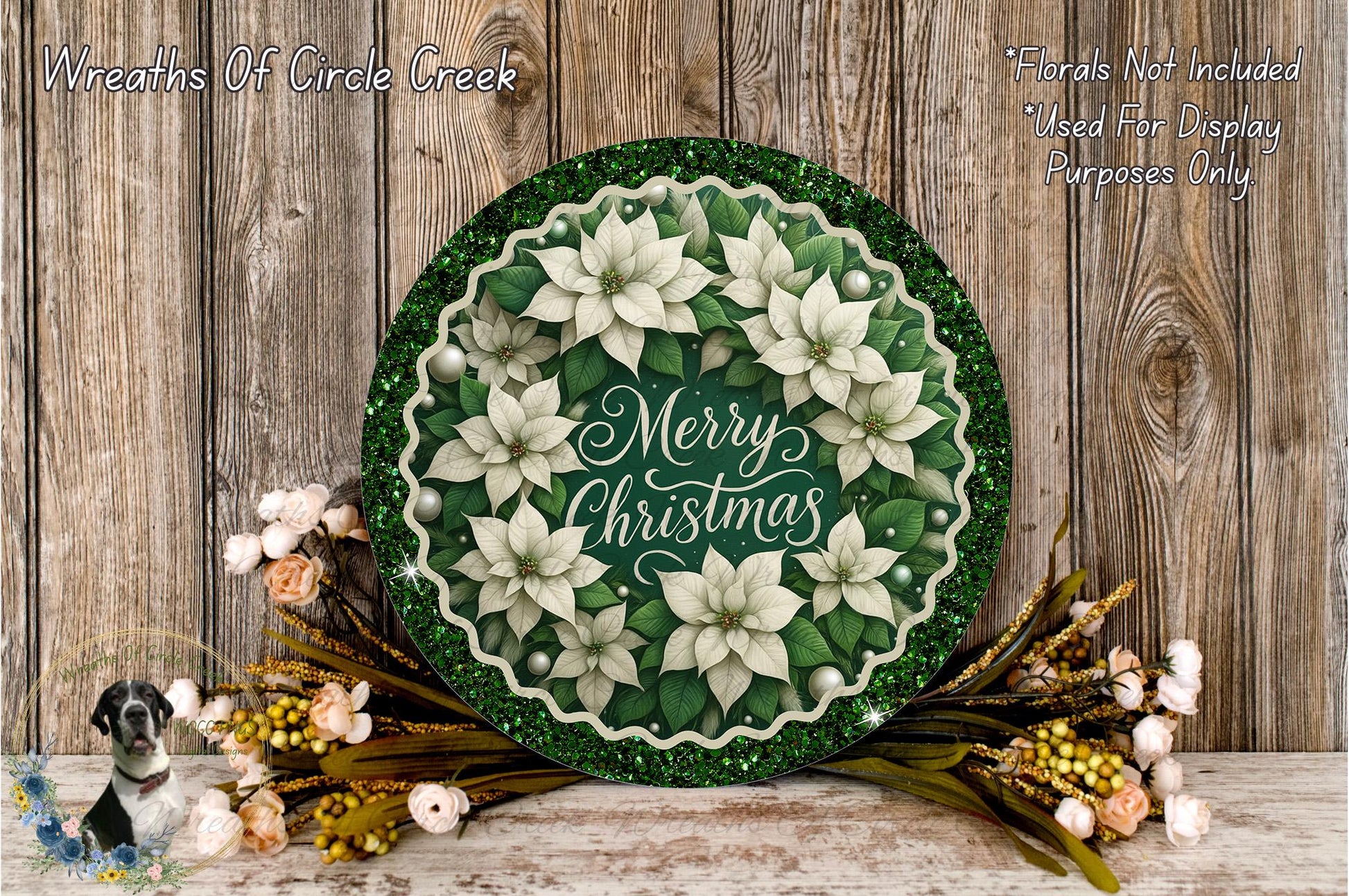 A festive wreath with white poinsettia flowers and greenery, surrounded by a green border and a "Merry Christmas" message, placed on a wooden surface.