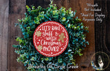 A wreath made of green leaves and a red circular sign with the text &quot;Let&#39;s Bake Stuff & Watch Christmas Movies&quot; is displayed on a wooden background.