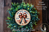 A wreath made of green leaves and a circular plaque with patriotic design elements, including a red, white, and blue ribbon and the text "God Bless America".