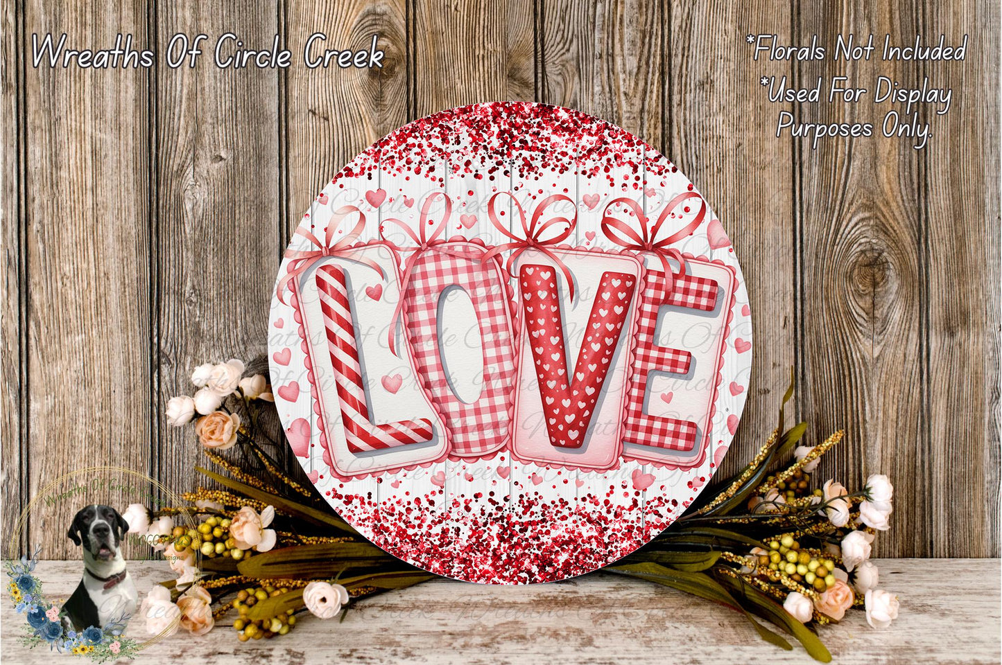 a decorative sign with the word "LOVE" written on it, surrounded by a wreath of flowers and a wooden background.