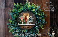 A wreath with a "Welcome" sign in the center, surrounded by a lush green wreath and featuring a small Santa Claus figurine.