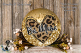 a decorative sign with a leopard print heart and the word "Be Mine" written on it, surrounded by a floral arrangement and placed on a wooden surface.