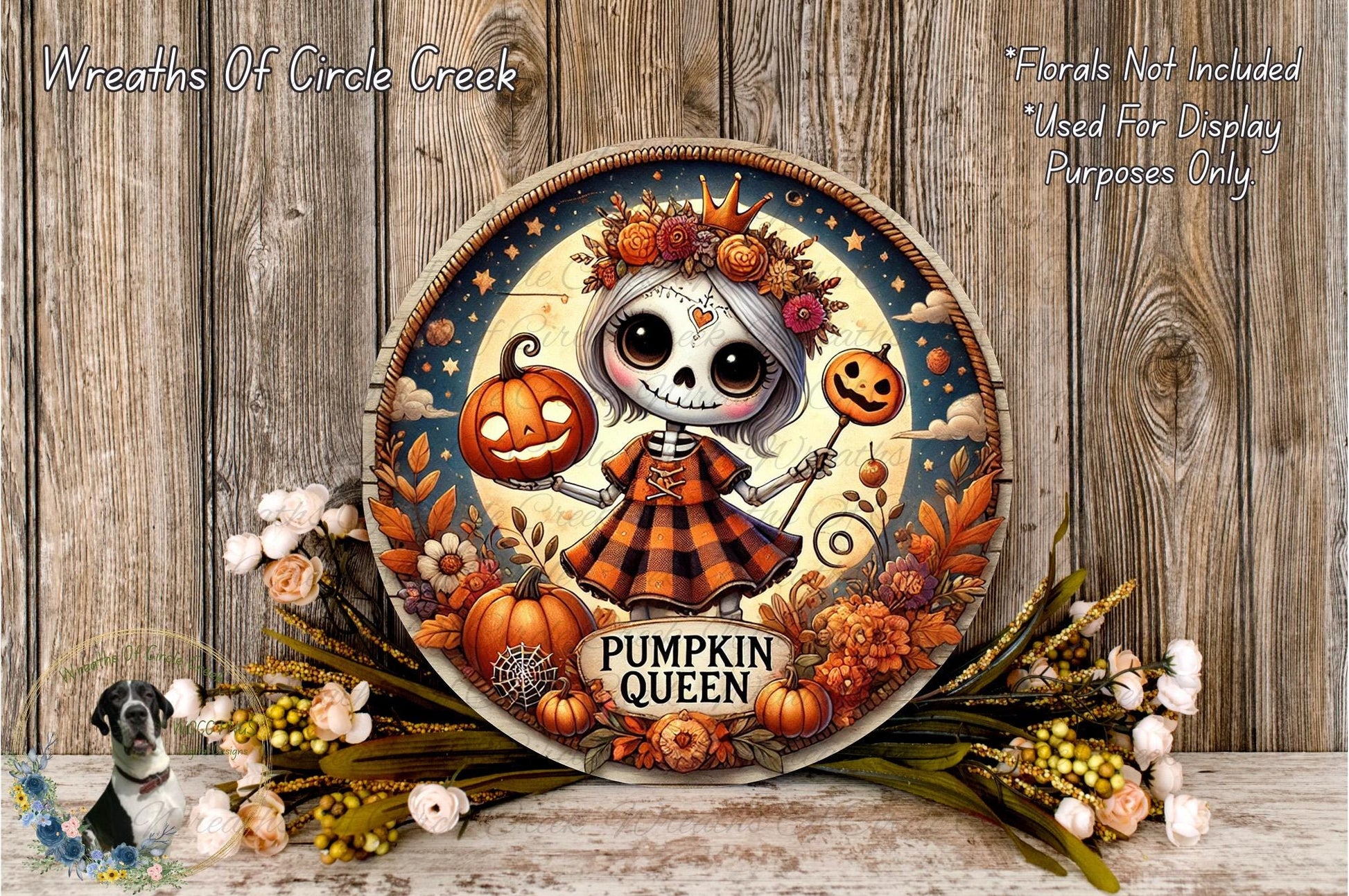 A decorative wreath featuring a skeleton girl holding a jack-o-lantern and a pumpkin, surrounded by autumn foliage and flowers.