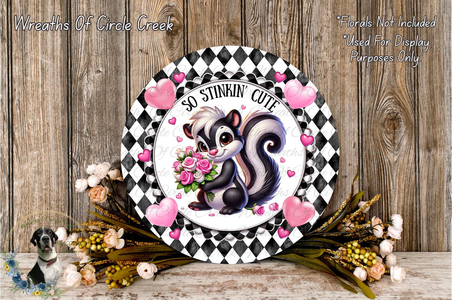 a decorative plate with a cartoon image of a skunk holding a bouquet of flowers, surrounded by hearts and flowers. The plate is placed on a wooden surface, and there are additional flowers and heart-shaped decorations around it.