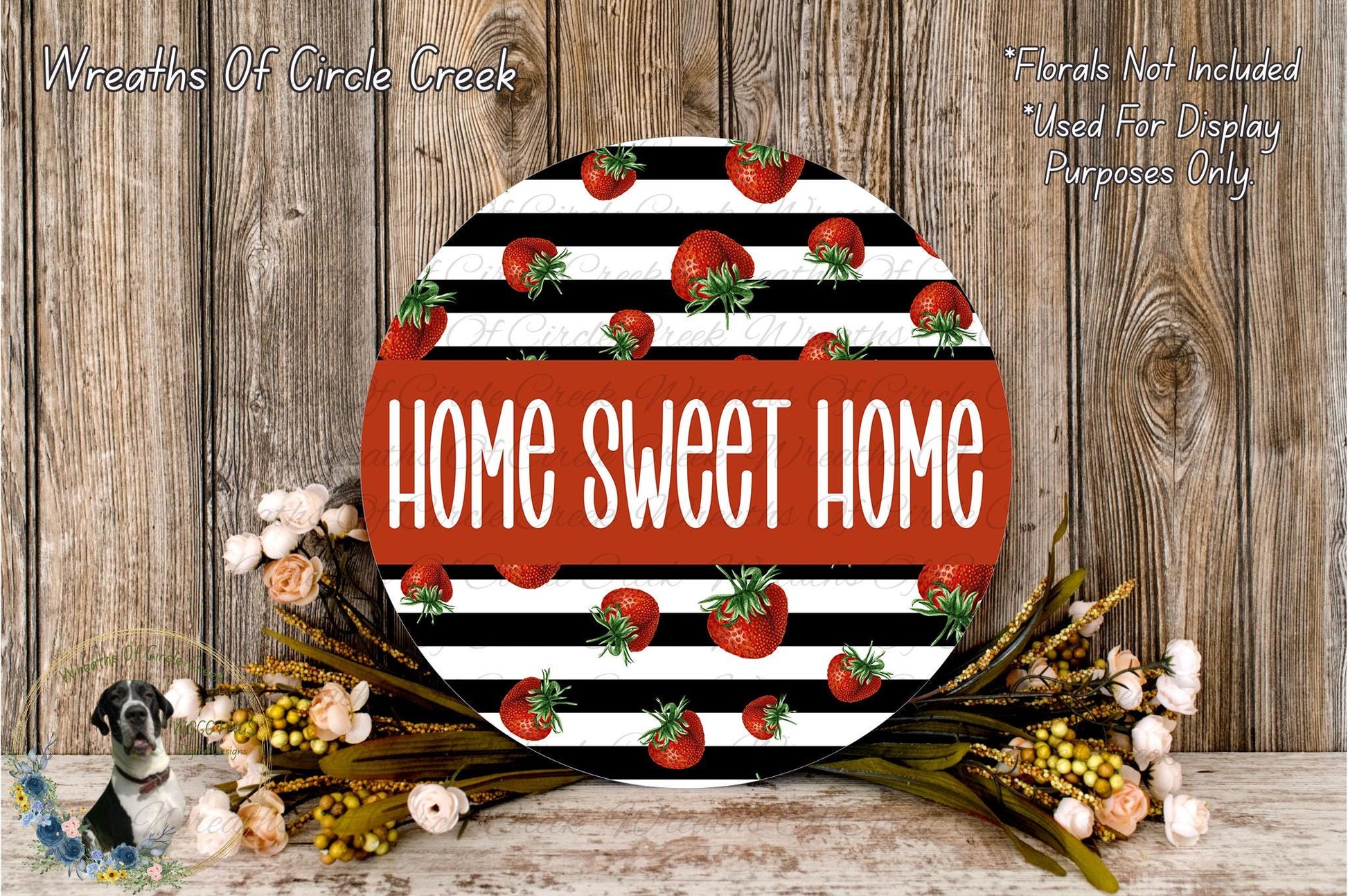 a round sign with the text "HOME SWEET HOME" in bold, red letters, surrounded by a decorative arrangement of flowers and greenery.