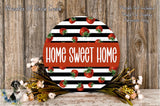 a round sign with the text "HOME SWEET HOME" in bold, red letters, surrounded by a decorative arrangement of flowers and greenery.
