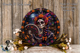 a decorative wreath with a skeleton wearing a colorful headpiece and holding a fan, surrounded by flowers and a wooden background.