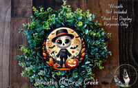 A Halloween-themed wreath featuring a skeleton wearing a top hat and holding a jack-o-lantern, surrounded by green foliage and a pumpkin.