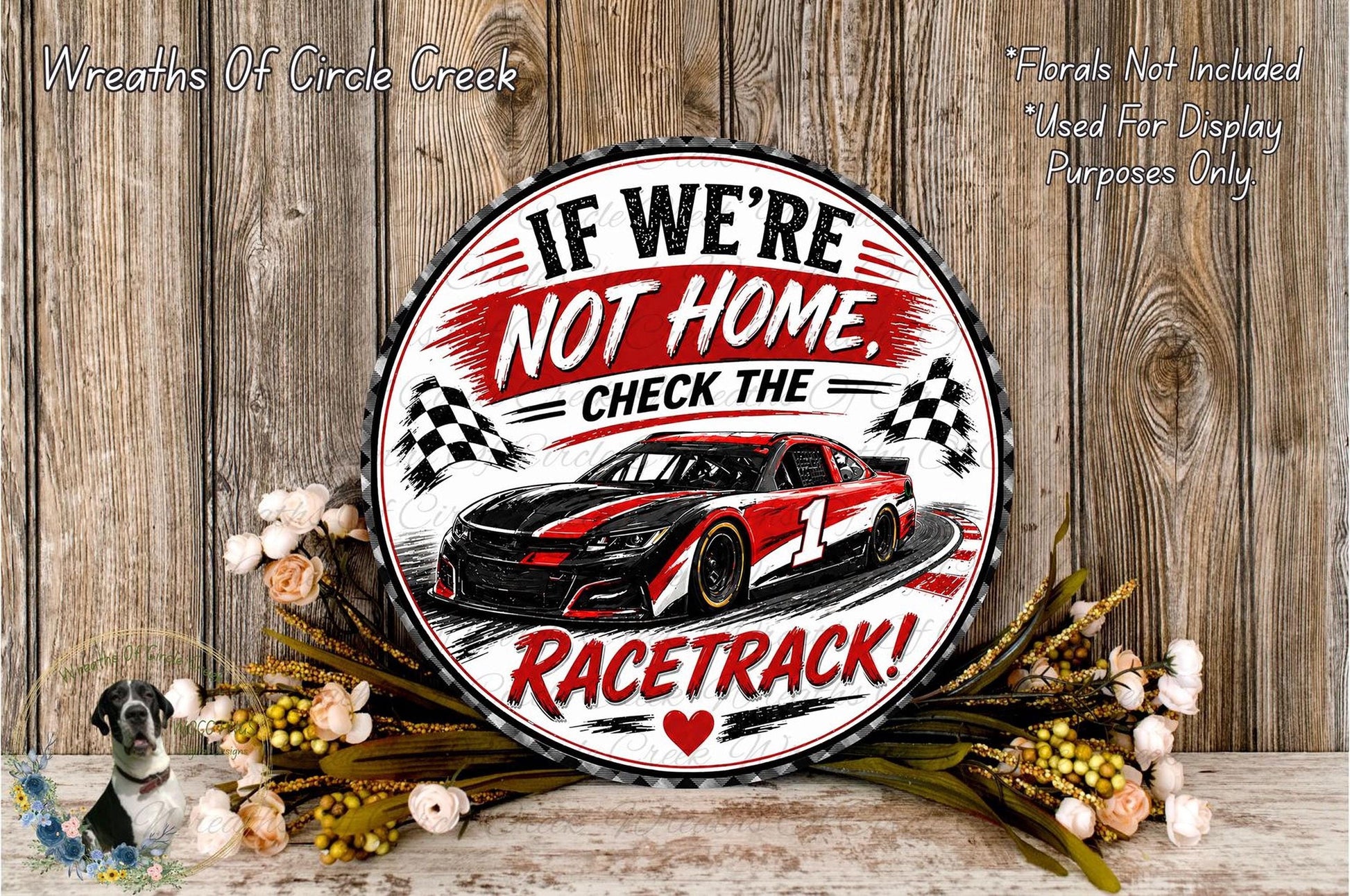 a decorative sign with a racing car design, surrounded by flowers and placed on a wooden surface.