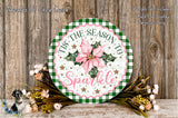 a round wooden sign with a floral design, surrounded by a wreath of flowers and greenery, placed on a wooden surface.