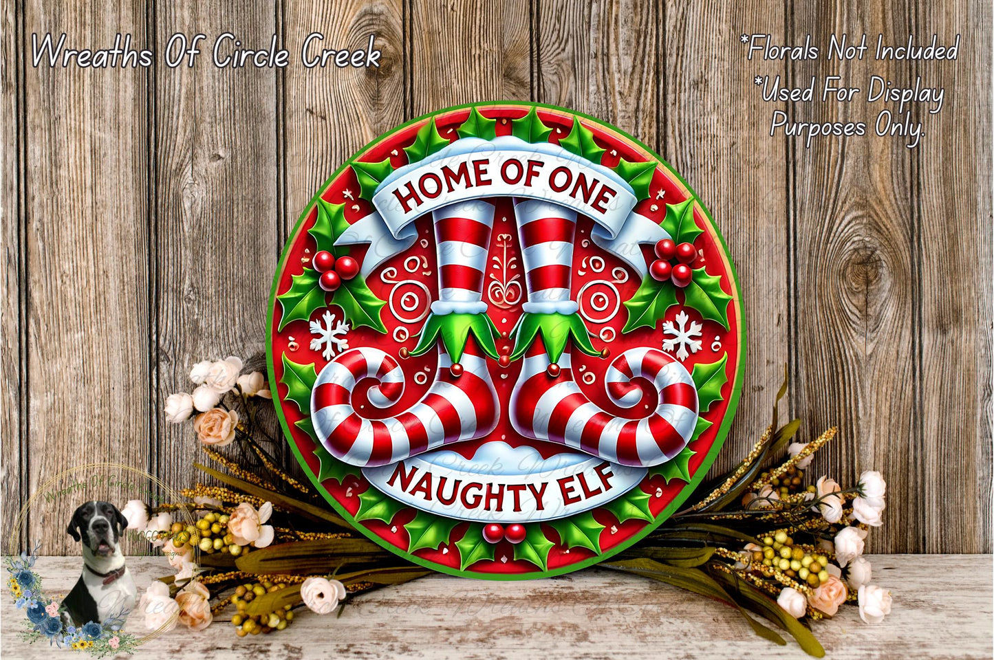 a festive wreath with the text "HOME OF ONE Naughty Elf" and a Santa Claus figurine. The wreath is displayed on a wooden surface, surrounded by flowers and greenery.