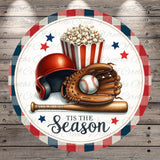 A baseball helmet, baseball, and baseball bat are arranged on a circular background with a red, white, and blue plaid border. The text "TIS THE SEASON" is displayed below the objects.