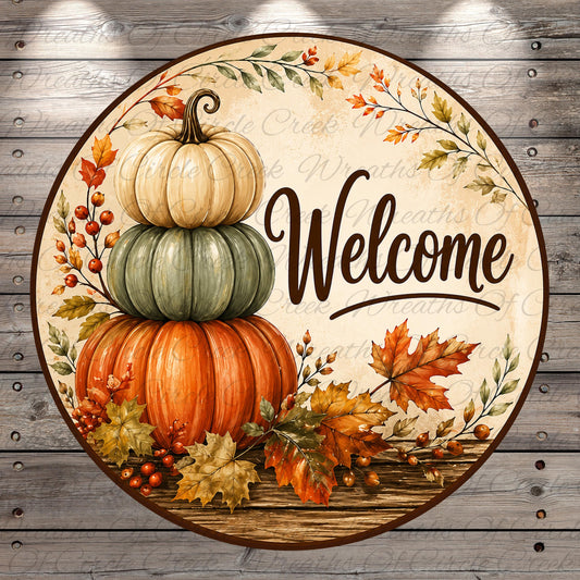A circular welcome sign with a stack of three pumpkins, autumn leaves, and berries, surrounded by a wreath of leaves and the word "Welcome" written on a wooden background.
