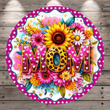 A round, decorative sign with a floral design and the word "MOM" prominently displayed in the center.
