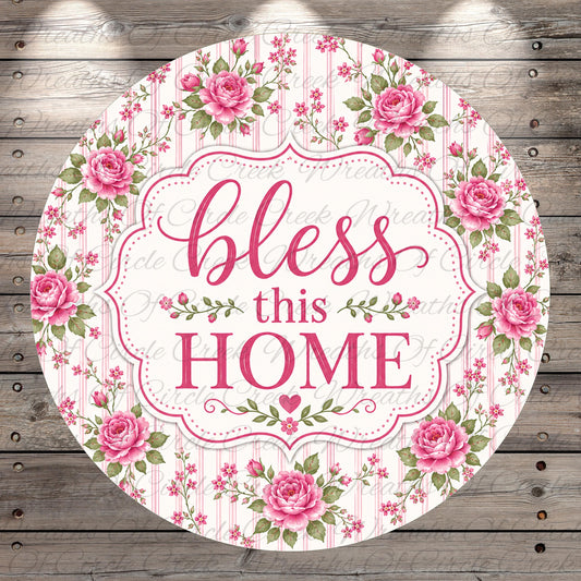 A round sign with a floral border and the text "bless this home" in pink and white.