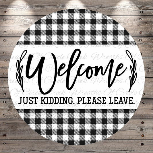 A circular sign with a black and white checkered pattern and the text "Welcome Just Kidding. Please Leave."