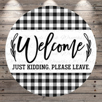 A circular sign with a black and white checkered pattern and the text "Welcome Just Kidding. Please Leave."