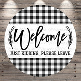 A circular sign with a black and white checkered pattern and the text "Welcome Just Kidding. Please Leave."