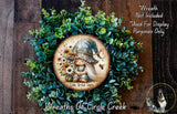 a wreath with a gnome and flowers, surrounded by greenery. The wreath is displayed on a wooden surface, and there is a small dog in the bottom right corner.