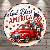 A circular patriotic design featuring a red truck with an American flag and flowers, surrounded by stars and the text "God Bless America".