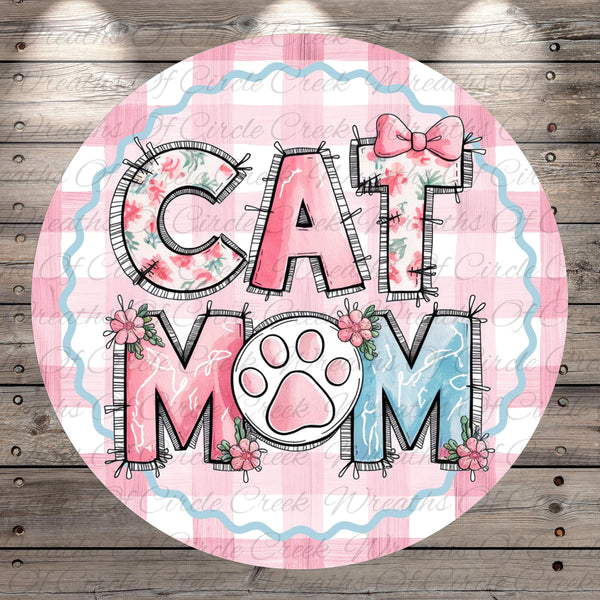 A round graphic with the text "CAT MOM" in a stylized font, surrounded by floral elements and a paw print.