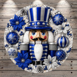 A nutcracker figure surrounded by various Christmas decorations, including blue and silver ornaments, snowflakes, and pine cones, all set against a wooden background.