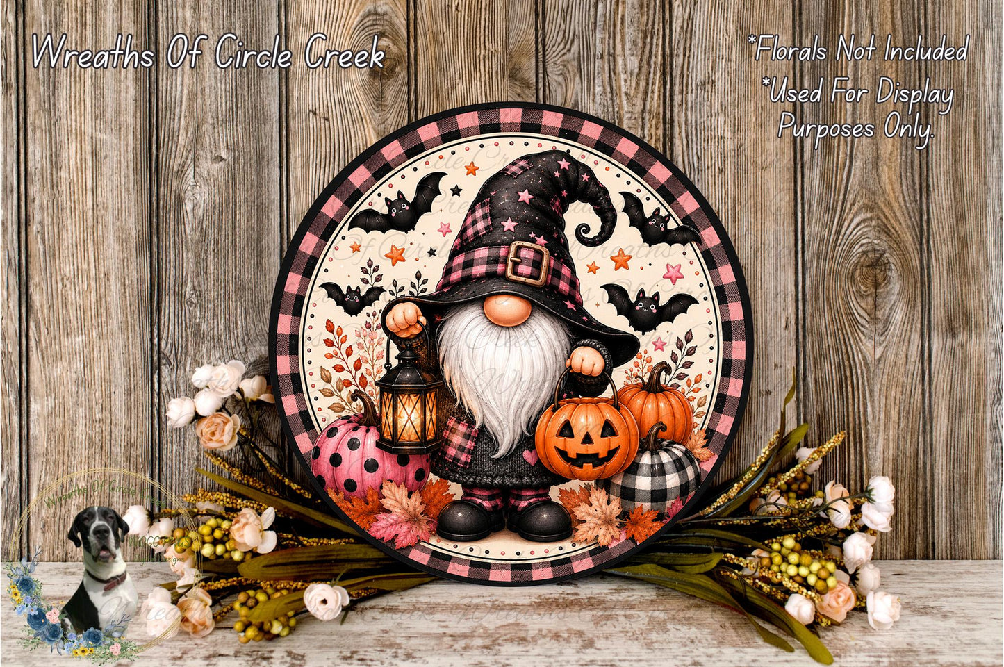 A gnome wearing a black hat and holding a lantern is surrounded by pumpkins, flowers, and bats, creating a festive Halloween scene.
