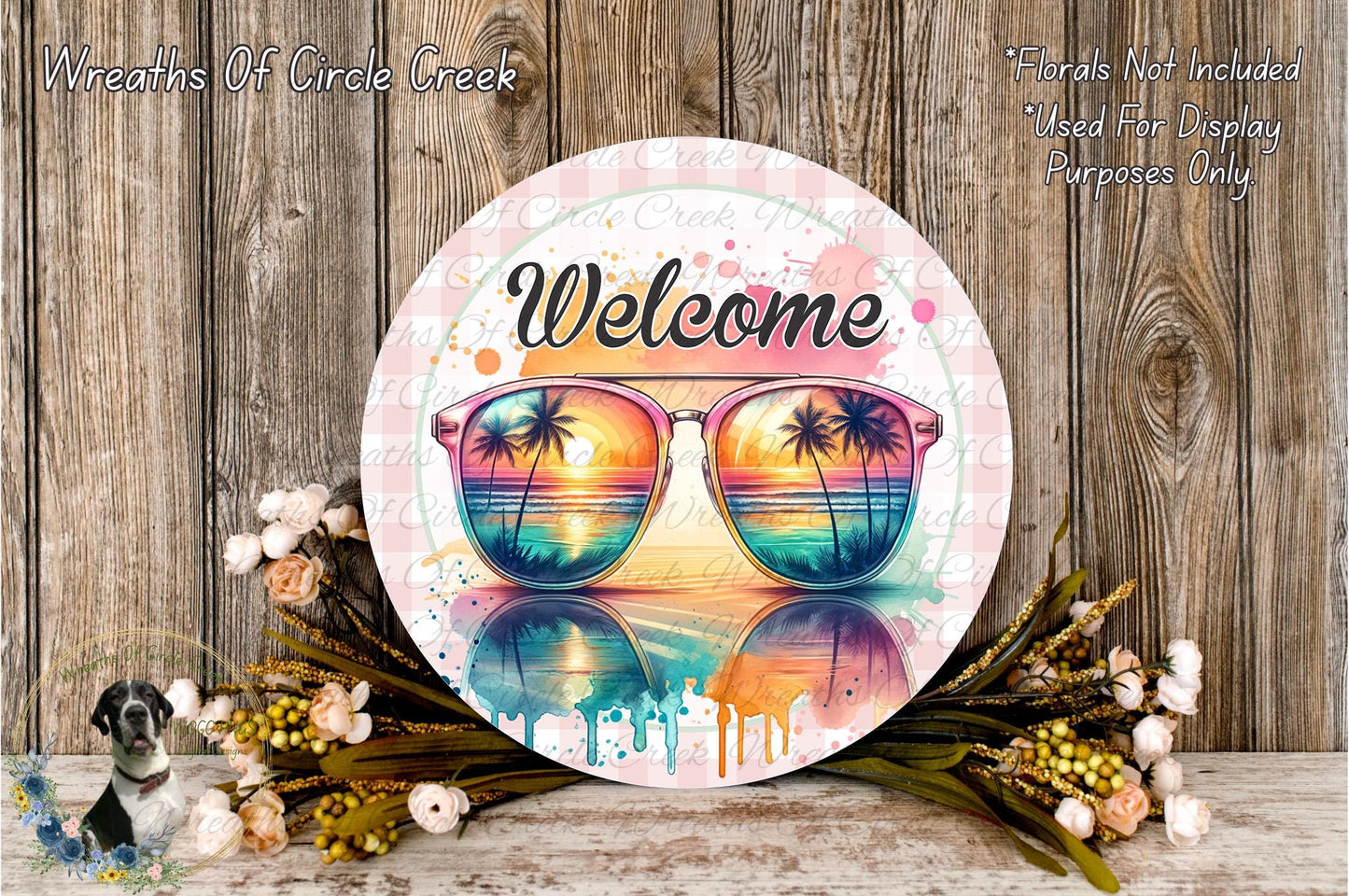 a circular sign with a beach scene and sunglasses, surrounded by flowers and greenery.