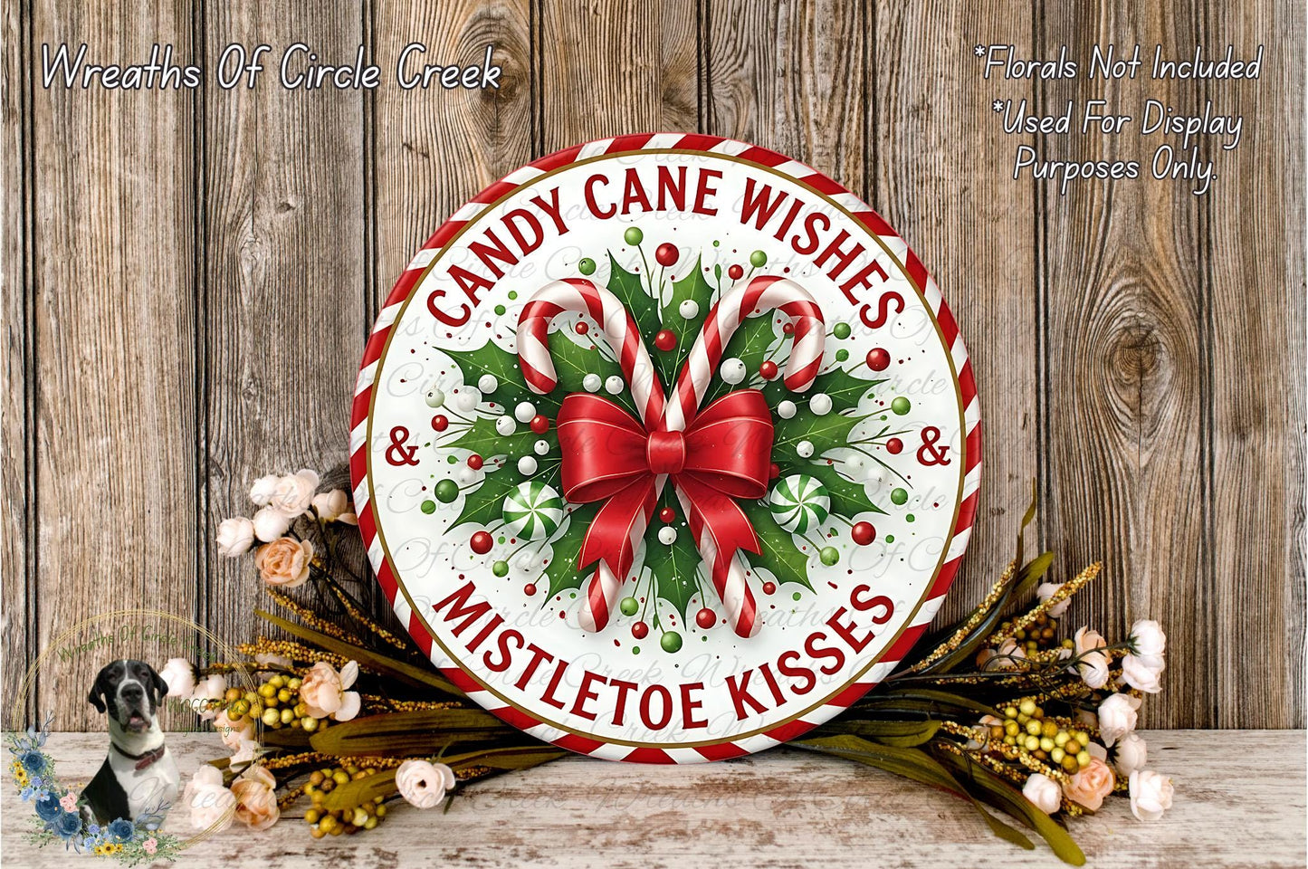 A festive wreath with candy canes and mistletoe kisses, surrounded by a floral arrangement, is displayed on a wooden surface.