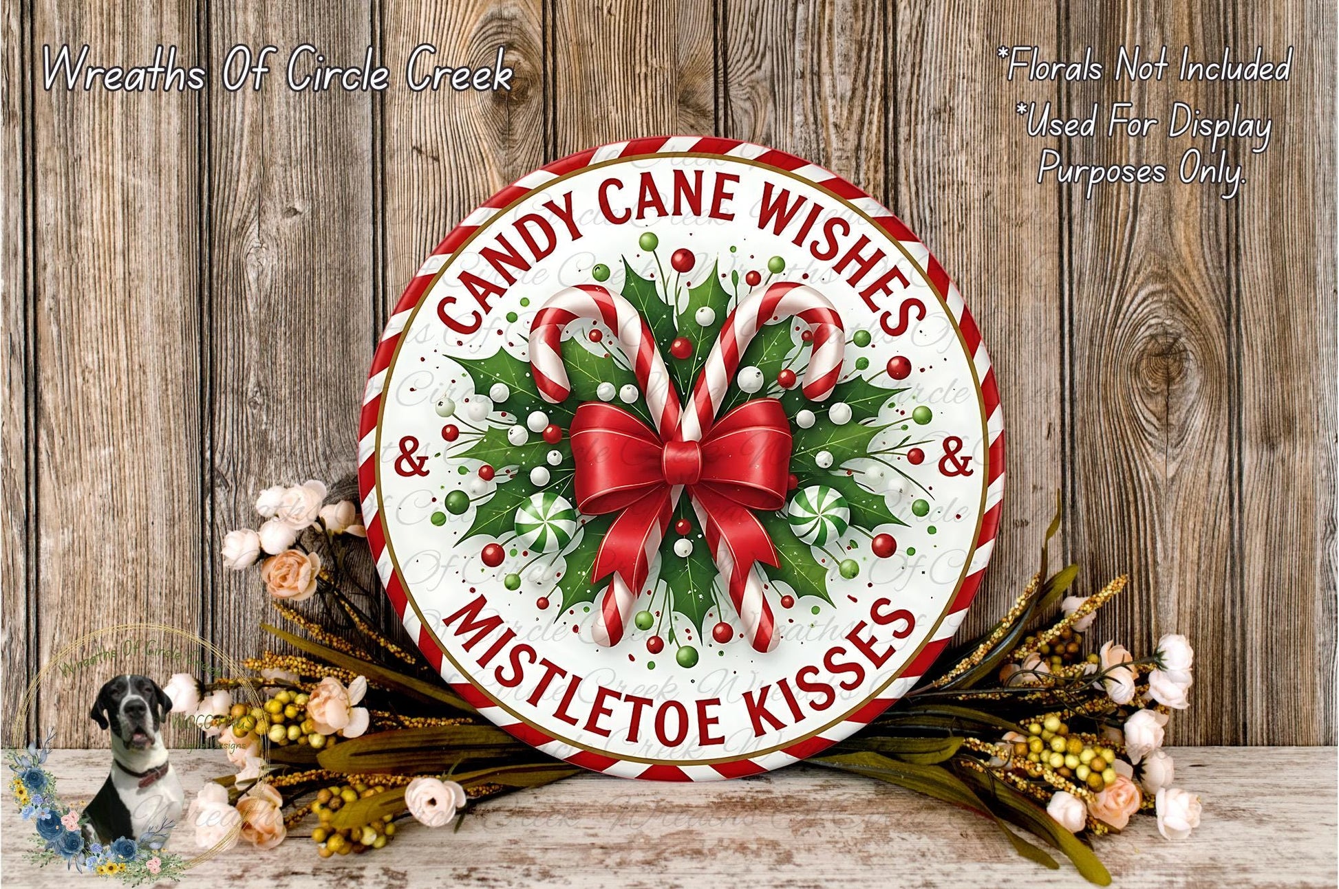 A festive wreath with candy canes and mistletoe kisses, surrounded by a floral arrangement, is displayed on a wooden surface.