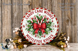 A festive wreath with candy canes and mistletoe kisses, surrounded by a floral arrangement, is displayed on a wooden surface.